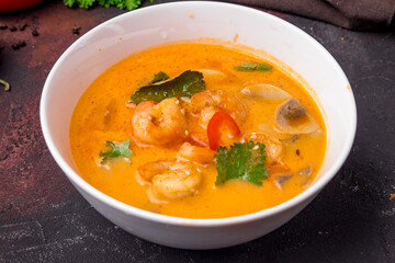 Tom Yam soup with shrimps on white bowl on dark table