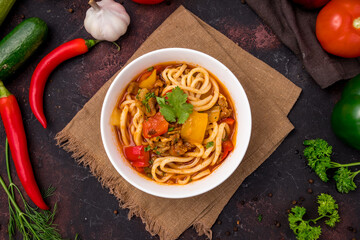 Lagman asian soup with meat, vegetables and noodles, dark table, uzbek cuisine top view