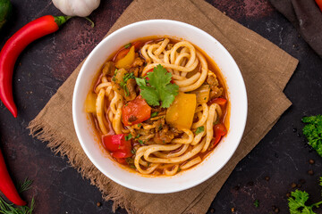 Lagman asian soup with meat, vegetables and noodles, dark table, uzbek cuisine top view