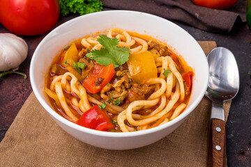 Lagman asian soup with meat, vegetables and noodles, dark table, uzbek cuisine