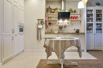 Modern new kitchen with a round dining table in the living room. Cabinets with built-in appliances...