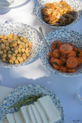 Bowls with healthy starters as chickpeas, carrots and cheese. Beautiful crockery with a pattern of small flowers