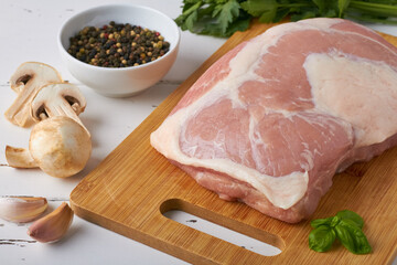 raw fresh pork ham pork gammon on a cutting board mixed peppercorns mushrooms parsley garlic on...