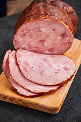 Homemade ham, sliced on a wooden table on a cutting board with spices and salt. Traditional ham homemade, ready to eat, delicious breakfast. The concept of meat products.