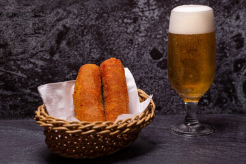 meat croquettes served in a basket with a glass of beer