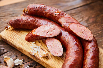 Homemade sausage with garlic cut into slices lies on a wooden table on a cutting board with spices...
