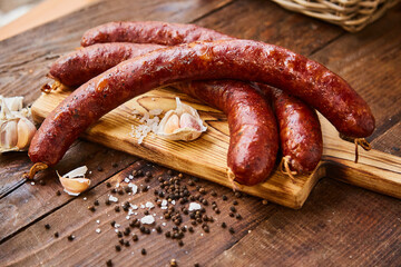 Homemade sausage with garlic cut into slices lies on a wooden table on a cutting board with spices...