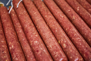 Factory for the production of meat products, boiled sausages. Traditional spicy sausage, ready to dry, lies on the table. The concept of handmade meat products. Sophistication.