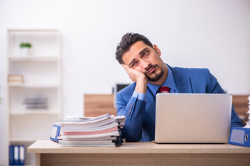 Young male employee unhappy with excessive work at workplace