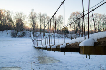 wooden bridge over the river has stuck into the ice and covered with the snow. colourful winter...