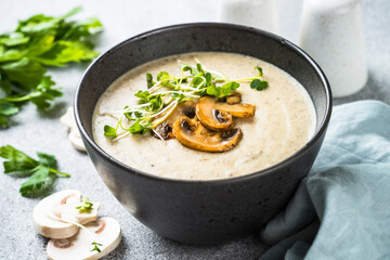 Mushroom Soup in black bowl on light stone table.