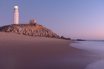 Sunset on the beach of Cape Trafalgar with the lighthouse in the background, Canos de Meca, Cadiz,...