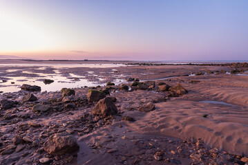 Fototapeta na wymiar Landscape with rocks and stones on the Barbate beach next to the mouth of the Barbate river at sunrise, Cadiz, Andalusia, Spain