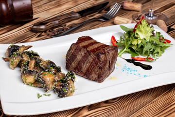 grilled Denver steak with grilled mushrooms on white plate