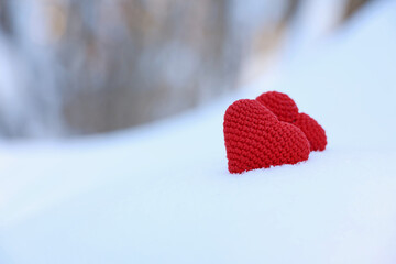 Love hearts, Valentine's card, two red knitted symbols of passion in the snow forest. Background for romantic event, celebration or winter weather	