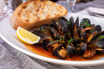 Fototapeta na wymiar Mussels in tomato sauce with lemon and grilled bread