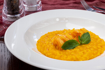 Risotto with fried shrimps on white plate , yellow color.