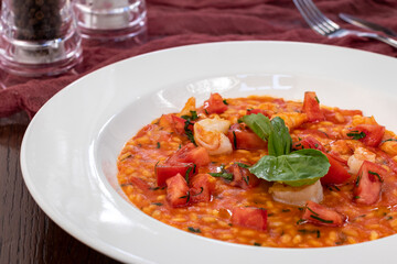 Risotto with shrimp and tomato sauce on white plate