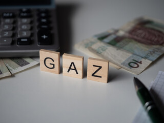 Gaz - napis z drewnianych kostek, podwyżki cen gazu, cena gazu, drogo, kalkulator, pieniądze, długopis, 
