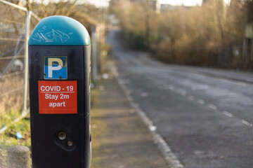 car parking meter with social distance warning sign
