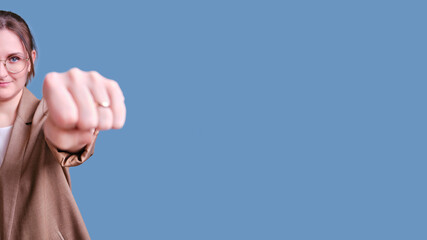 Woman teacher with fist gesture forward on studio blue background, banner copy space