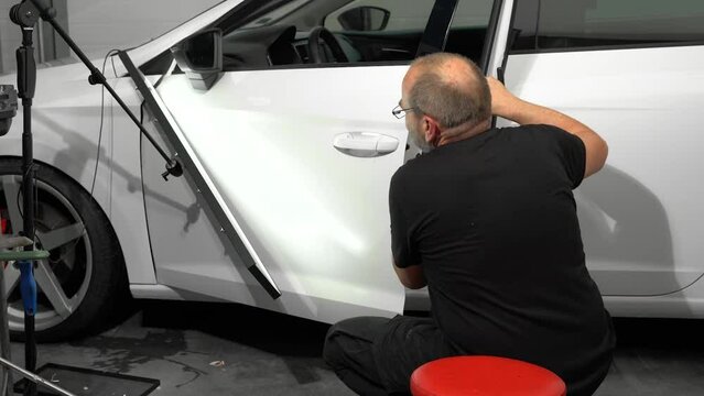 Process Of Repairing Dent On Car Left Door Surface in Car Repair Shop. Technician Is Using Tools For Paintless Dent Repair.