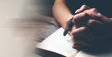 woman praying on book holding cross