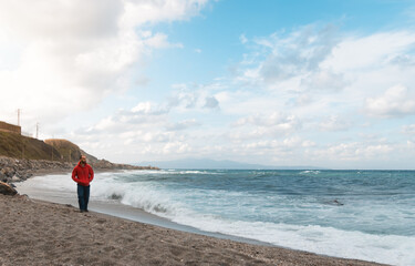 Man walking on a cloudy day on a beach with churning water