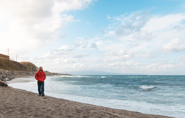 Man walking on a cloudy day on a beach with churning water