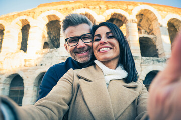 Happy couple of senior tourist having fun taking a selfie in front of famous monument of Italy - Vacation, tourism and travel concept - obrazy, fototapety, plakaty