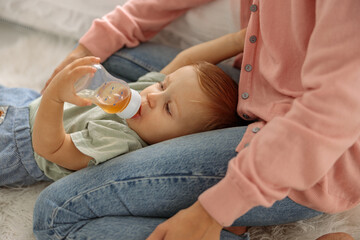 Adorable baby boy on floor drinking from a bottle