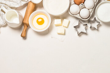 Ingredients for baking at white table. Flour, sugar, eggs and utensils. Top view with copy space.