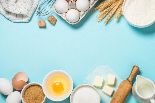 Baking background. Baking ingredients at blue table. Flour, sugar, eggs and utensils. Top view with copy space.