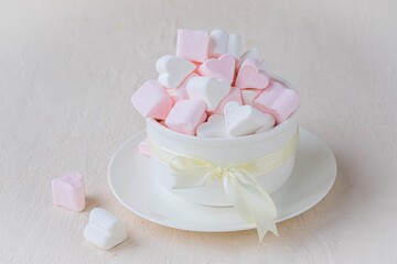 Pink and white marshmallow hearts in a white ceramic bowl on a light concrete background. Valentine's day concept.