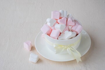 Pink and white marshmallow hearts in a white ceramic bowl on a light concrete background. Valentine's day concept.