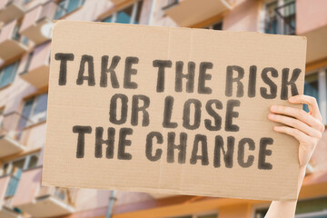 The phrase " Take the risk or lose the chance " on a banner in men's hand with blurred background. Corporate. Company. Advice. Inspire. Loss. Entrepreneur. Explore. Perspective. Successful. Confident