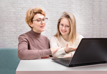 Cute smiling teen girl and mother using laptop in the house. Mother and Daughter at Home. Teenage Girl.