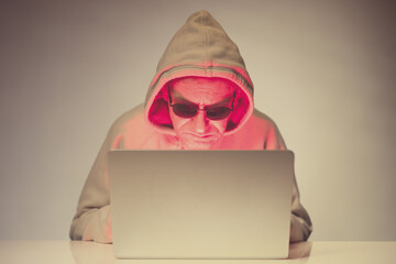 Older criminal man using computer for remote money robbery