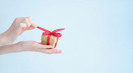 Festive composition. Consists of hands holding a gift box on a blue background.