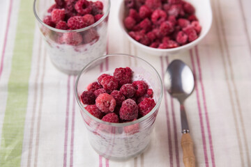 Dessert of yogurt, chia seeds, frozen raspberries in a glass