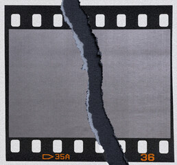 single 35mm dia film frame with empty cell on white copy paper background and torn paper edge...