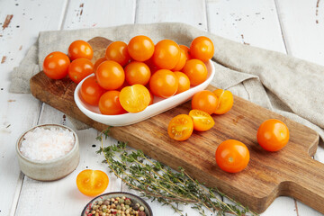 Fresh yellow cherry tomatoes on white wooden background