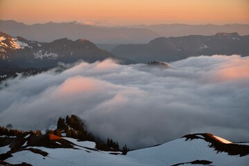 Clouds in mountain valley with snow covered peaks. View form above. Rocky mountain National park....