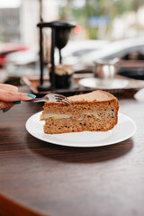 Female hand cutting slice of cake and banana