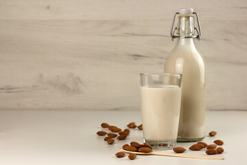 A bottle and a glass with alternative dairy free almond milk and nuts. Lactose free beverage