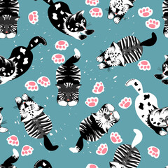 Seamlesspattern of kittens in black,white and gray colors and footprints on blue background.Cute childish texture for printing on fabrics and paper.Original and trendy hand drawn vector illustration.