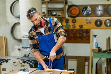 Young handsome caucasian carpenter working with clamps in workshop