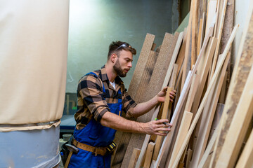 Handsome carpenter carefully picking boards for his next project