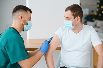 Fototapeta premium Doctor making a vaccination in the shoulder of patient Disabled person, Flu Vaccination Injection on Arm, coronavirus, covid-19 vaccine disease preparing for human clinical trials vaccination shot.