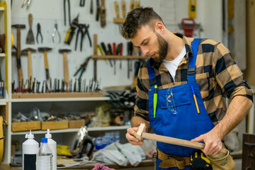 Handsome young carpenter sanding peace of wood